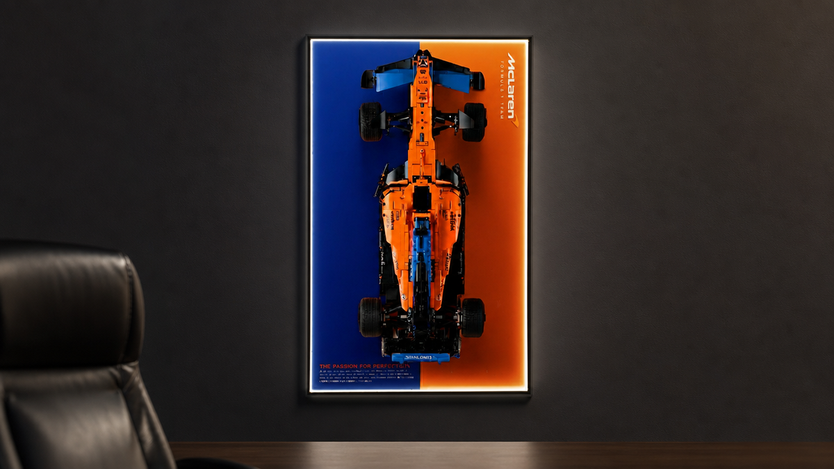 LEGO McLaren F1 42141 mounted in a Flexra Vault wall-mount display frame on a dark feature wall in an adult collector's study